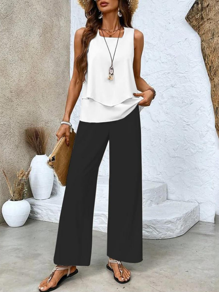 A woman wearing a layered sleeveless top with leaf-print wide-leg pants, light and elegant.