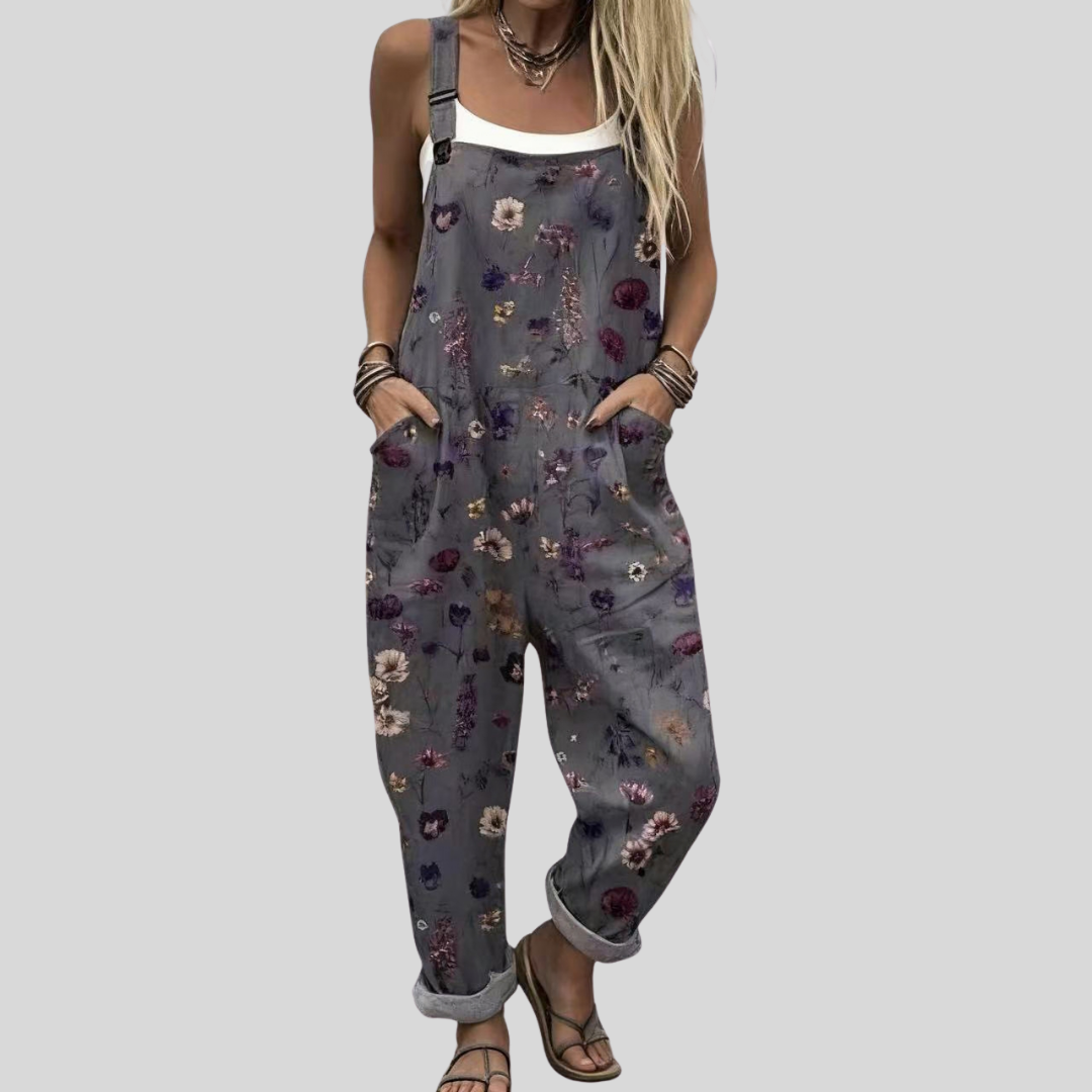 A woman wearing relaxed grey overalls with a small colourful floral print and a plain top.