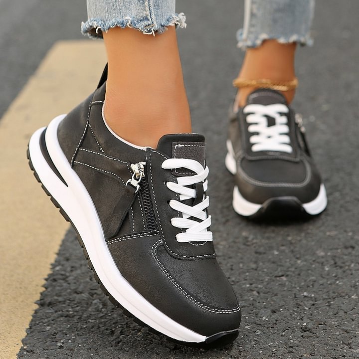A woman wearing cushioned orthopaedic sneakers with a side zip