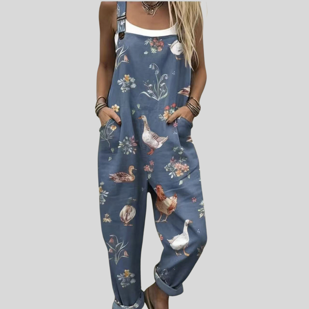 A woman wearing soft blue overalls printed with white geese and small flowers, relaxed outdoors.