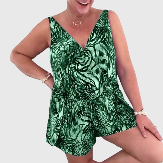 A woman in a blue printed swim playsuit with a flowing top and shorts, relaxed by the pool.