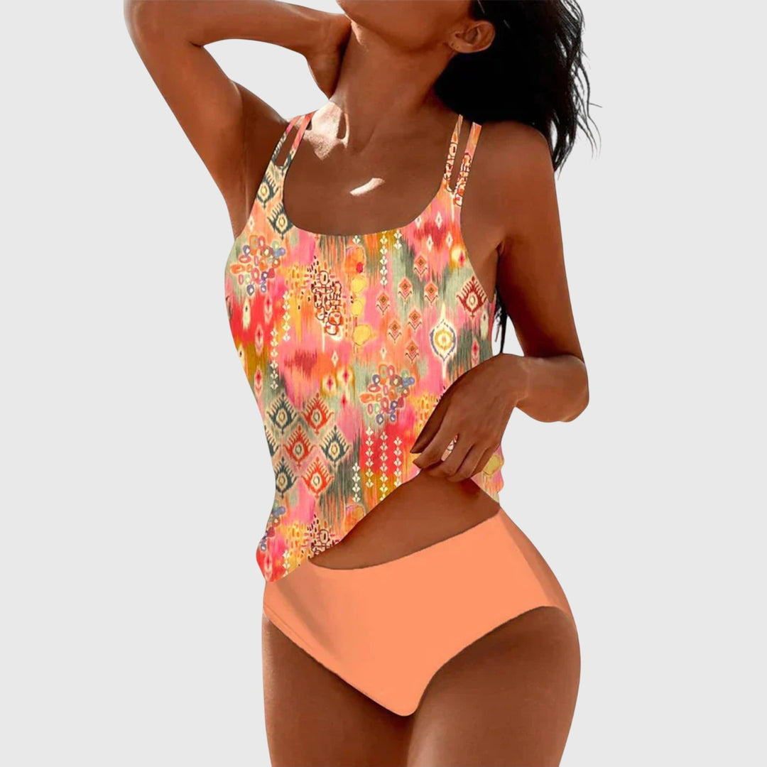 A woman by the sea in a coordinated printed two-piece swimsuit set, relaxed in the summer sun.