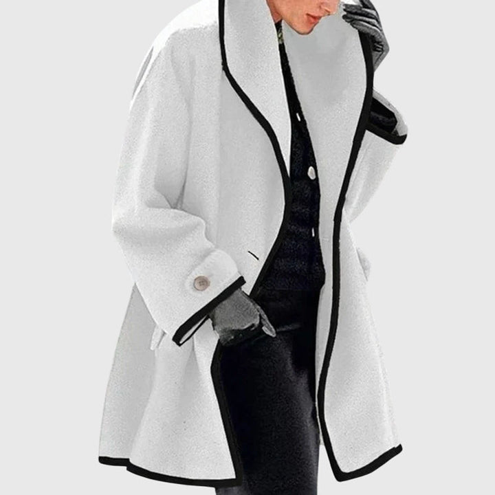 A woman wearing a blue swing-cut jacket with a black contrast trim
