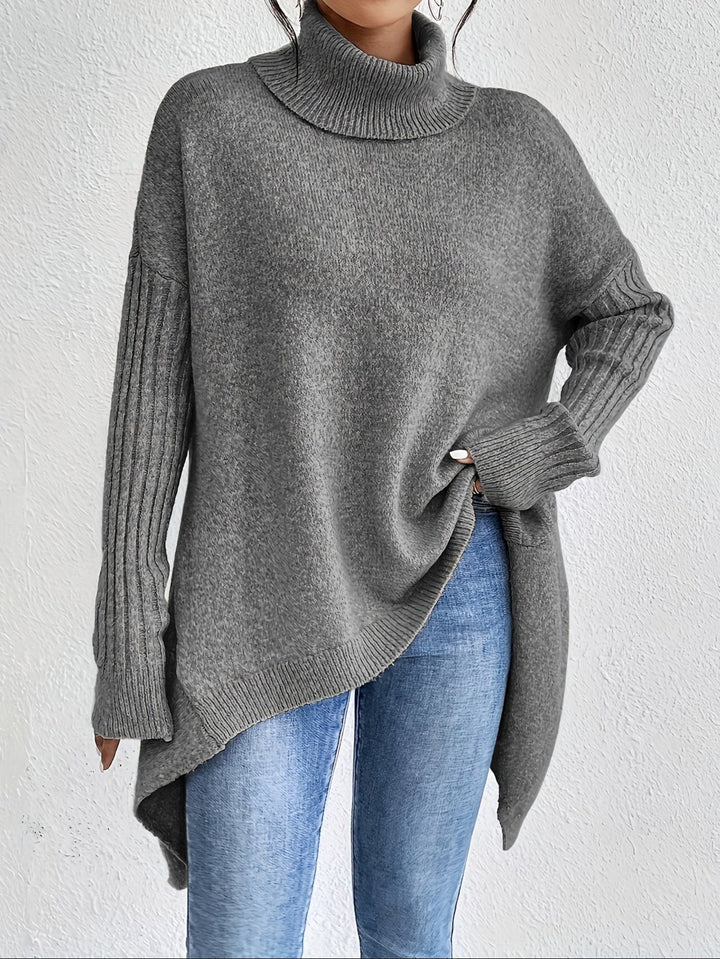 A woman wearing a stand-collar sweater with a chic asymmetric drape, warm and polished.