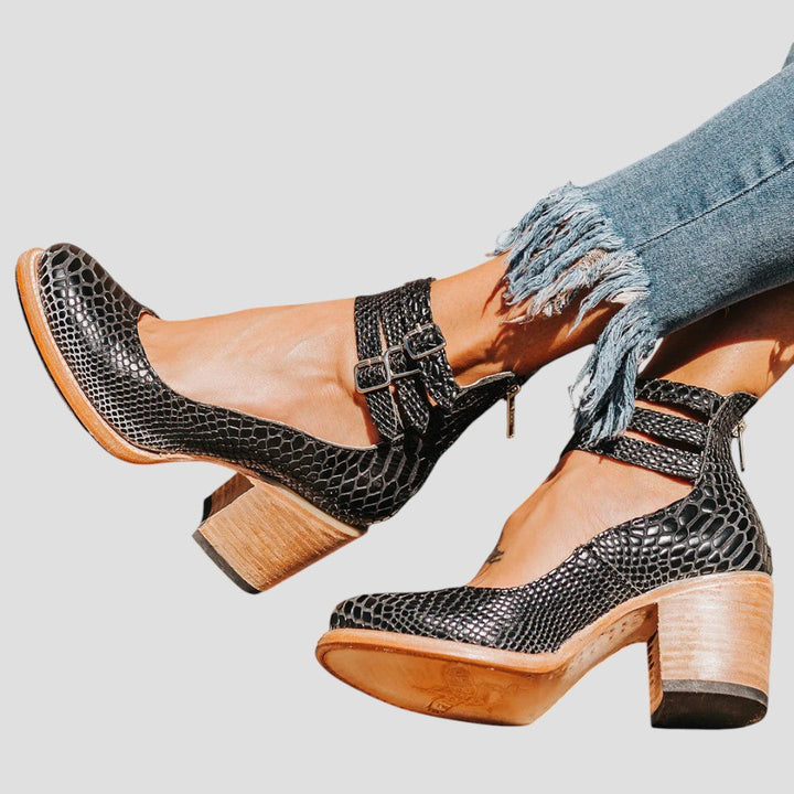 A woman wearing cognac block-heel pumps with triple ankle straps and a rounded toe.