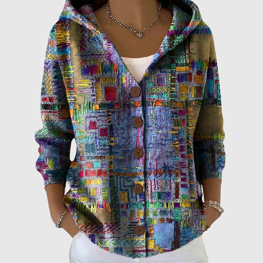 A woman wearing a hooded button cardigan in a bold multicoloured abstract print over a white top.