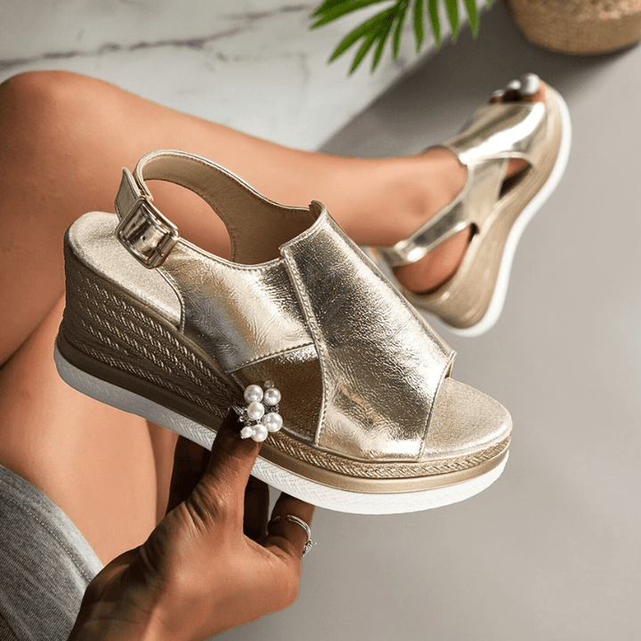 A woman wearing gold metallic sandals with a cushioned insole and wide, supportive fit.