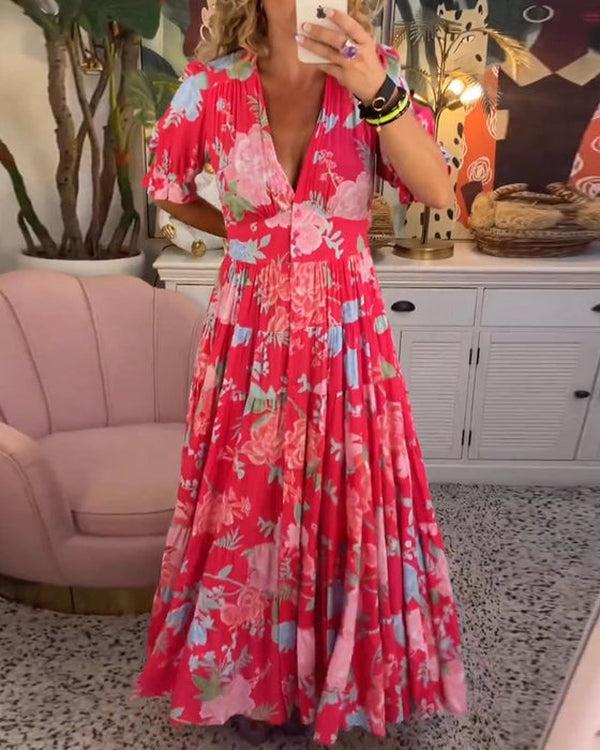A woman wearing the Dawn bold floral maxi dress with a flowing full-length skirt at a garden gathering.