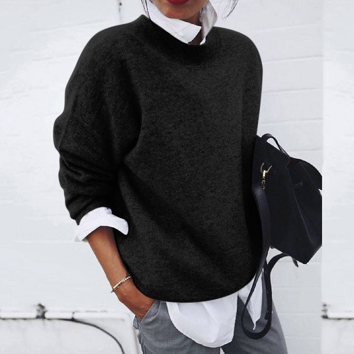A woman wearing a soft mustard round-neck sweater with an elegant modern shape, relaxed and warm.