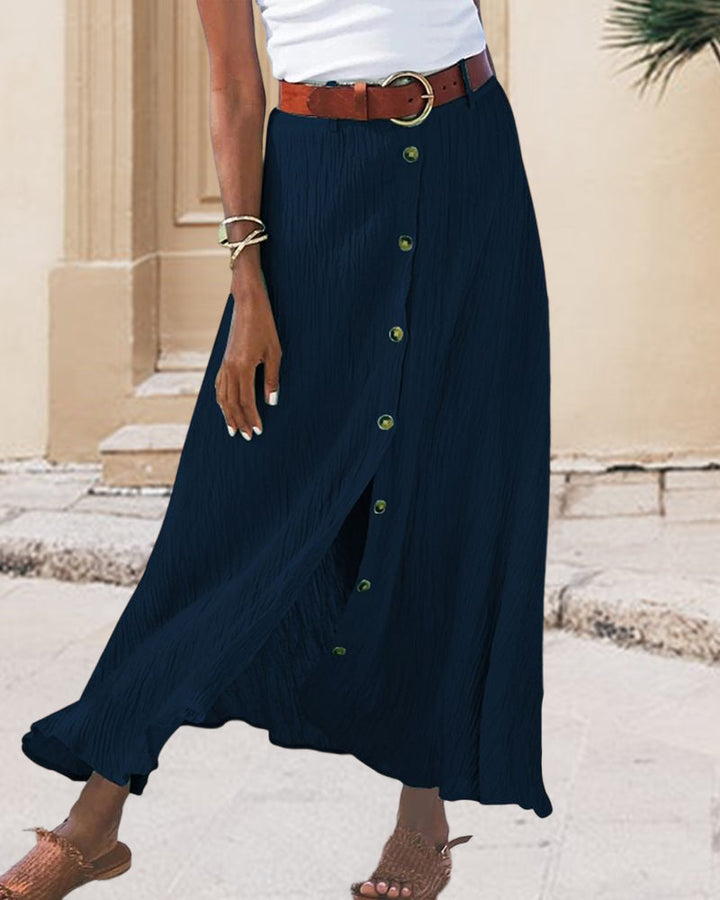 Woman wearing a flowing high-waisted button skirt with a tucked-in top, walking outdoors.