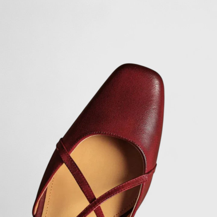 Burgundy closed square-toe flats with criss-cross instep straps and a buckled slingback.
