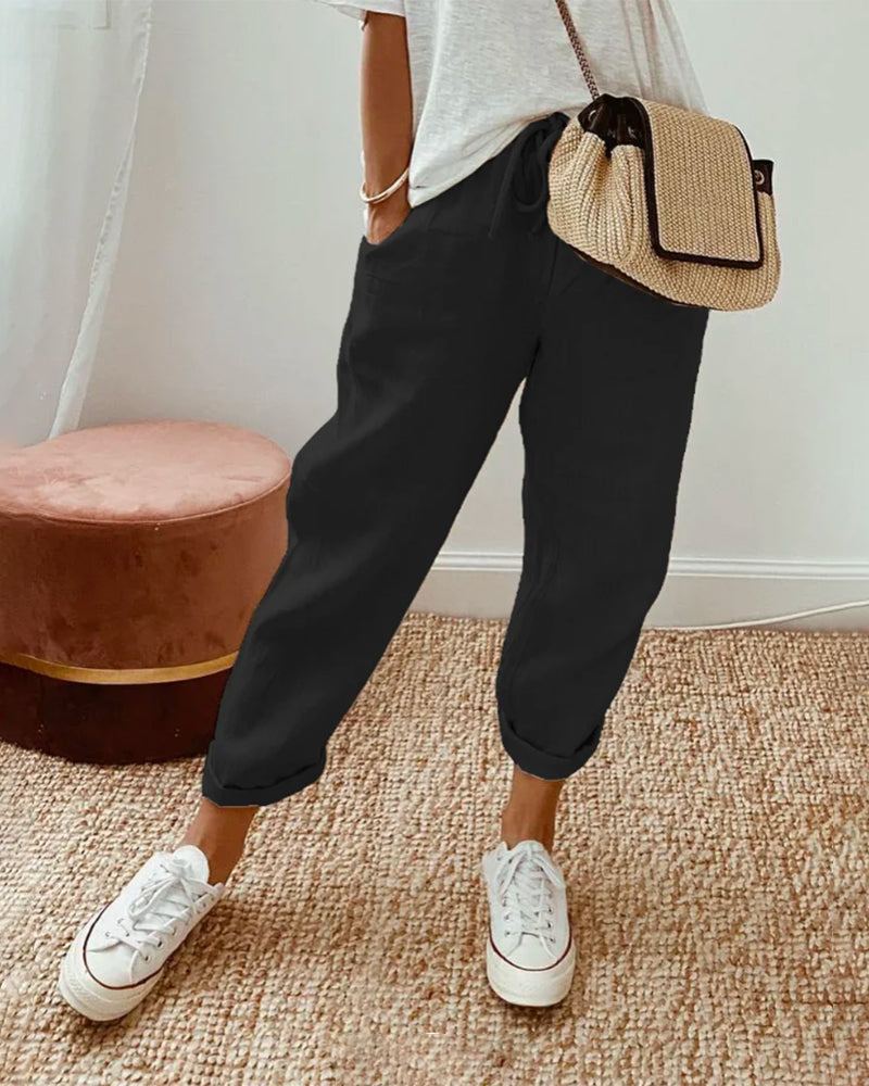 A woman wearing flowing elegant pants with a soft elastic waist and deep pockets.