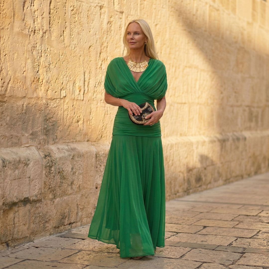 A woman wearing a flowing kelly green dress at an evening occasion.