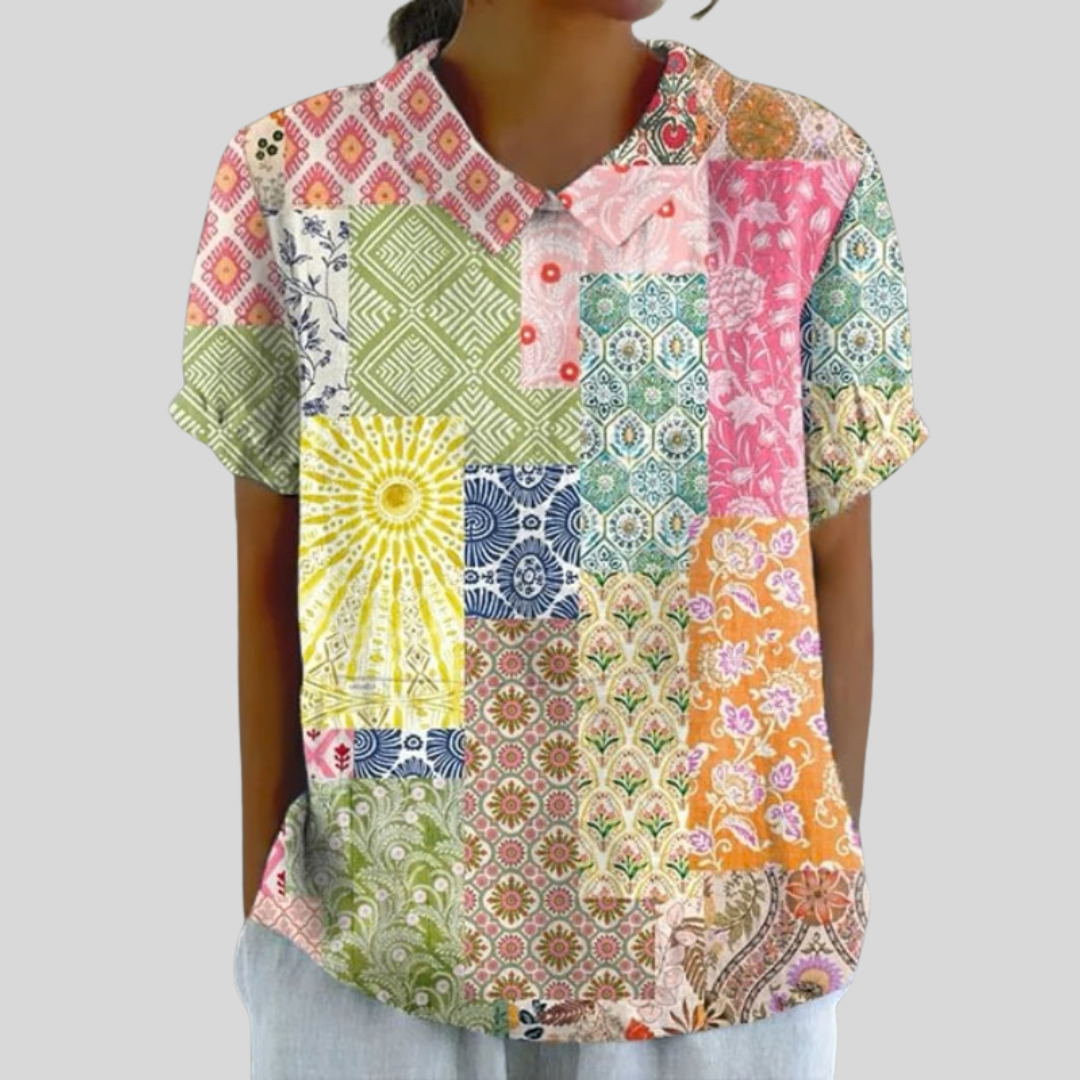 A woman wearing a flowing polo collar top in a colourful patchwork print, looking relaxed and well dressed.