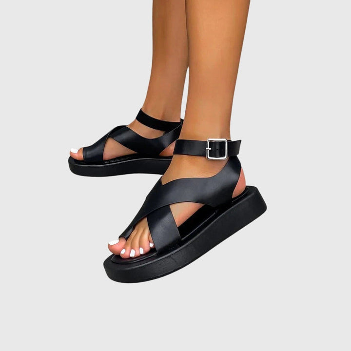 A woman in black chunky platform sandals with an ankle strap, standing confidently, feet cushioned and supported.