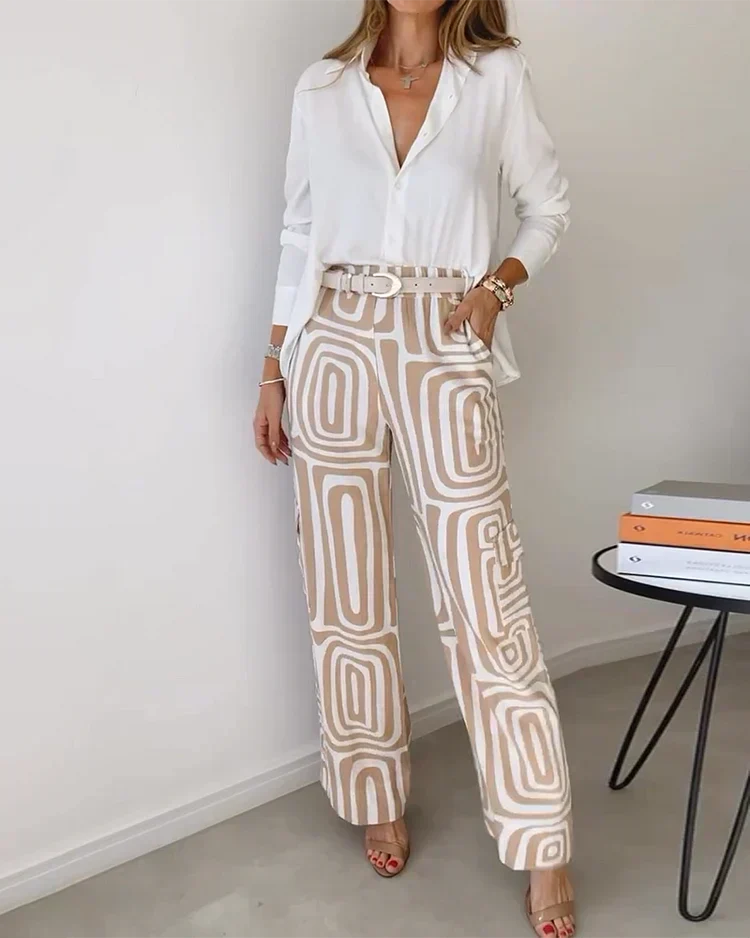 A woman wearing a plain button-up top with geometric-print pants and a belt at the waist.