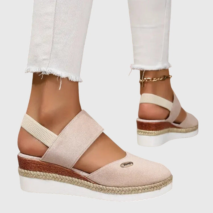 Black closed-toe wedge espadrilles with a wide stretch strap and a braided-trim platform wedge.