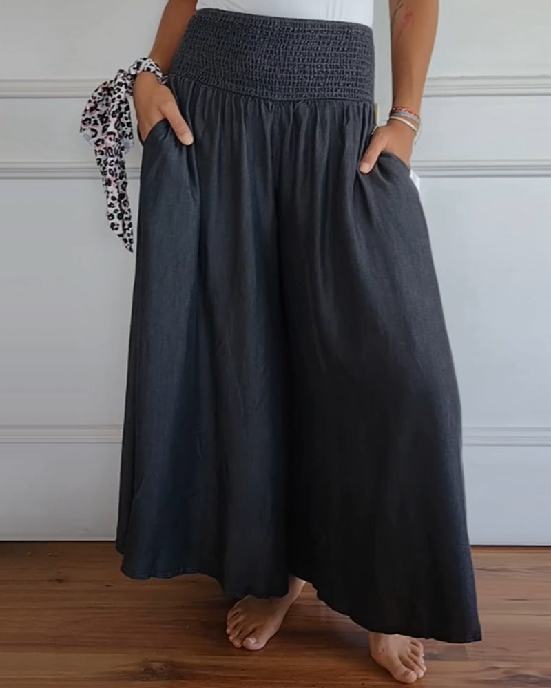 Woman wearing high-waist wide-leg pants with a tucked-in blouse, mid-stride.