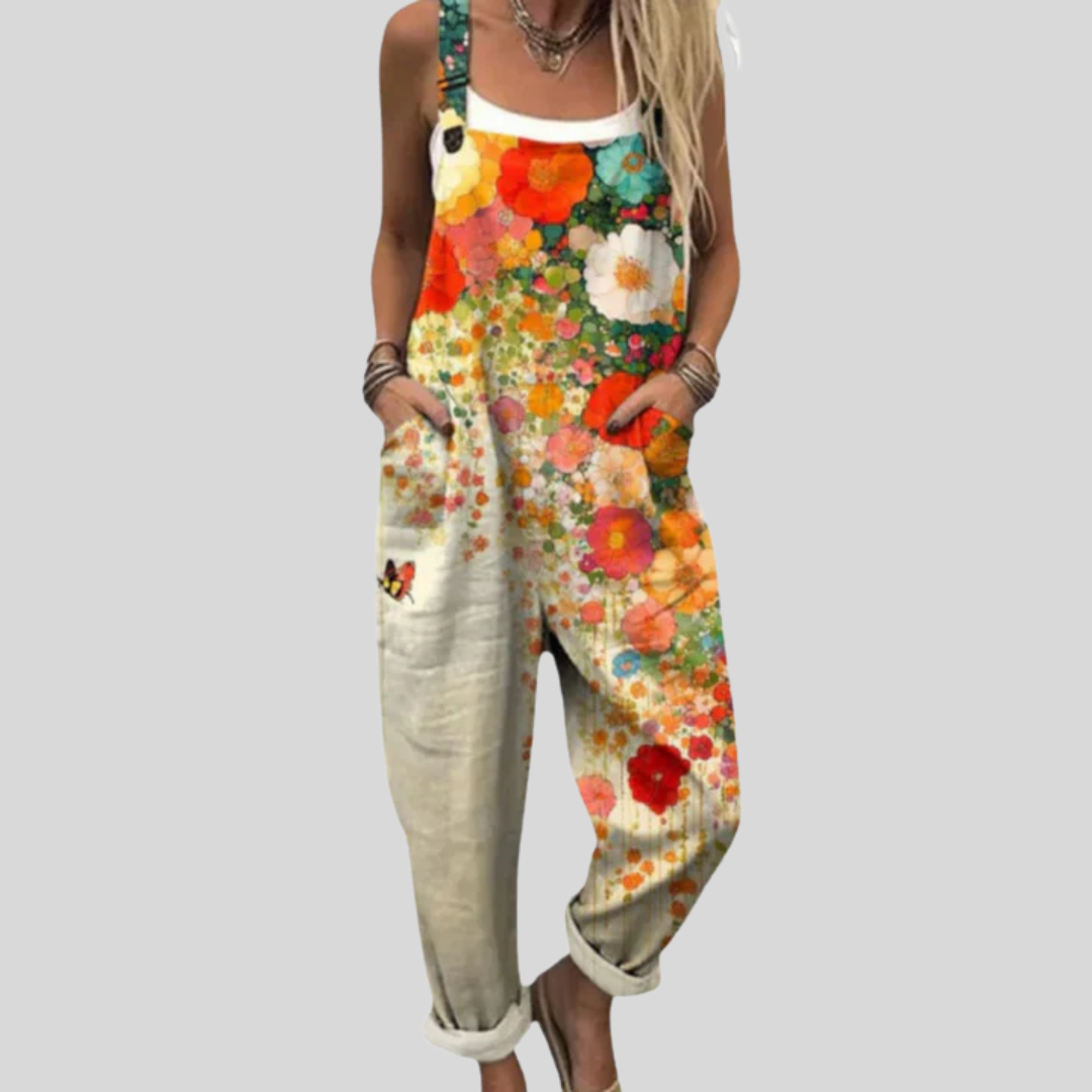 Woman wearing overalls printed with a rich sea of poppies and daisies in warm orange and yellow tones.