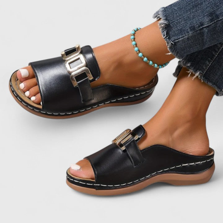 A woman wearing white comfort slides with a golden front trim and a cushioned sole.