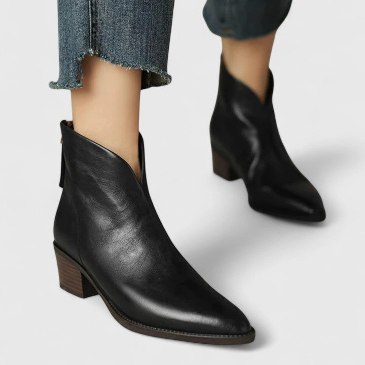 Woman wearing black elegant boots with tailored pants on a city footpath.