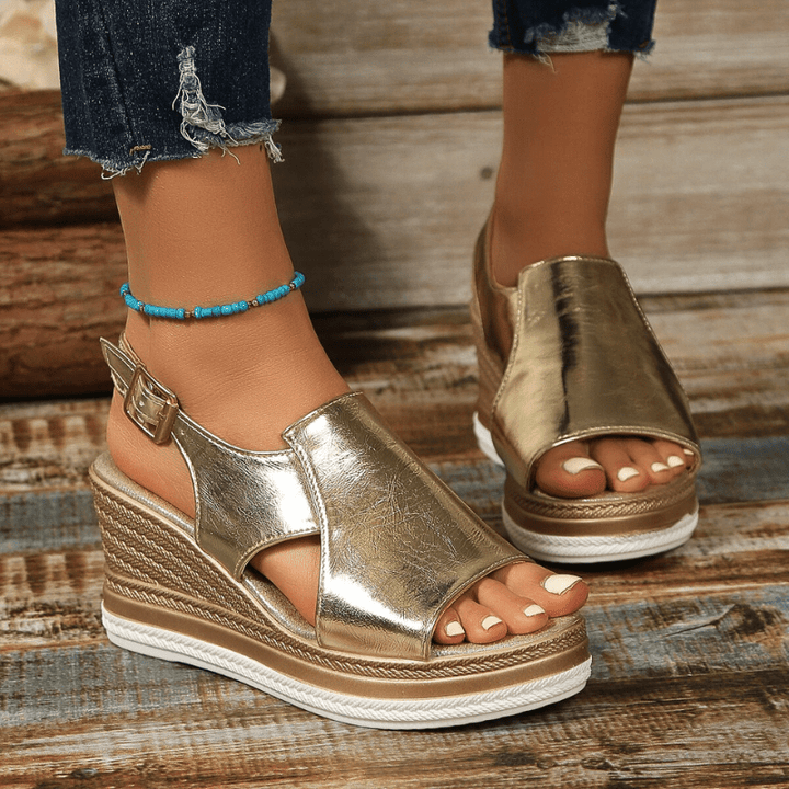 A woman wearing gold metallic sandals with a cushioned insole and wide, supportive fit.