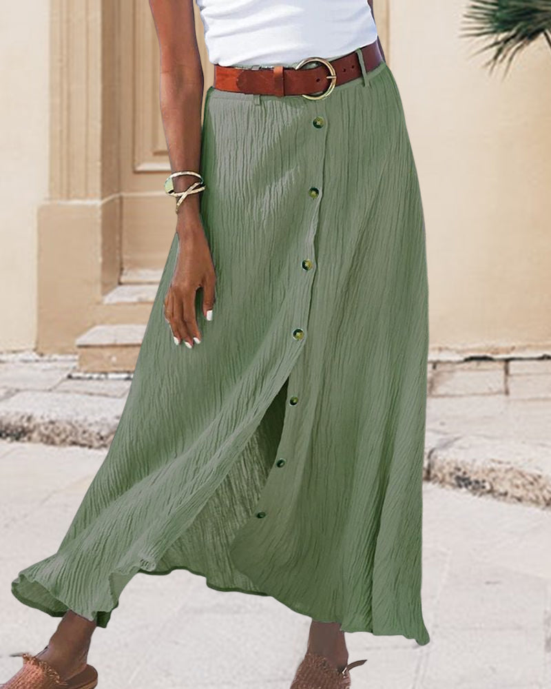 Woman wearing a flowing high-waisted button skirt with a tucked-in top, walking outdoors.