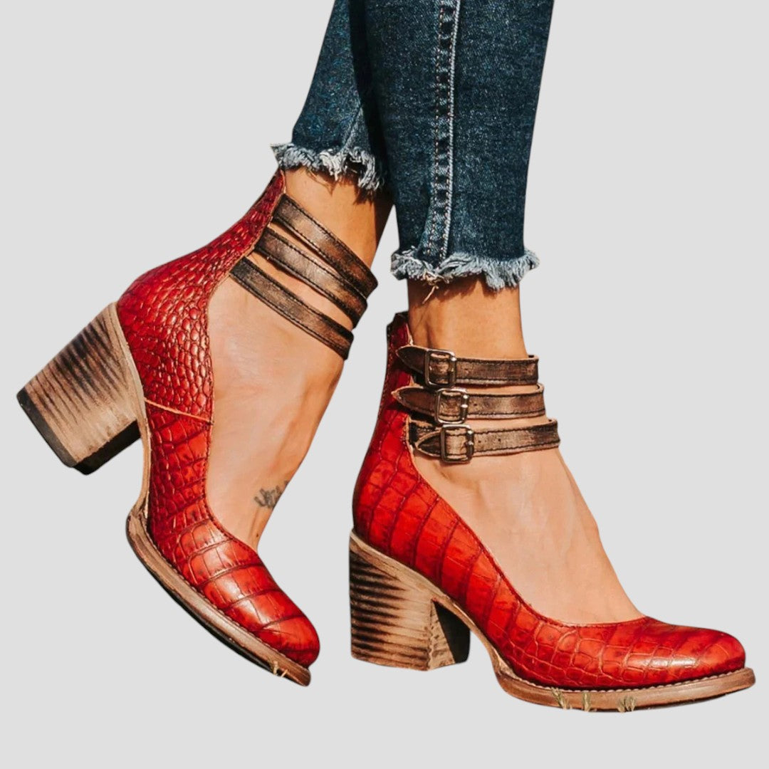 A woman wearing cognac block-heel pumps with triple ankle straps and a rounded toe.