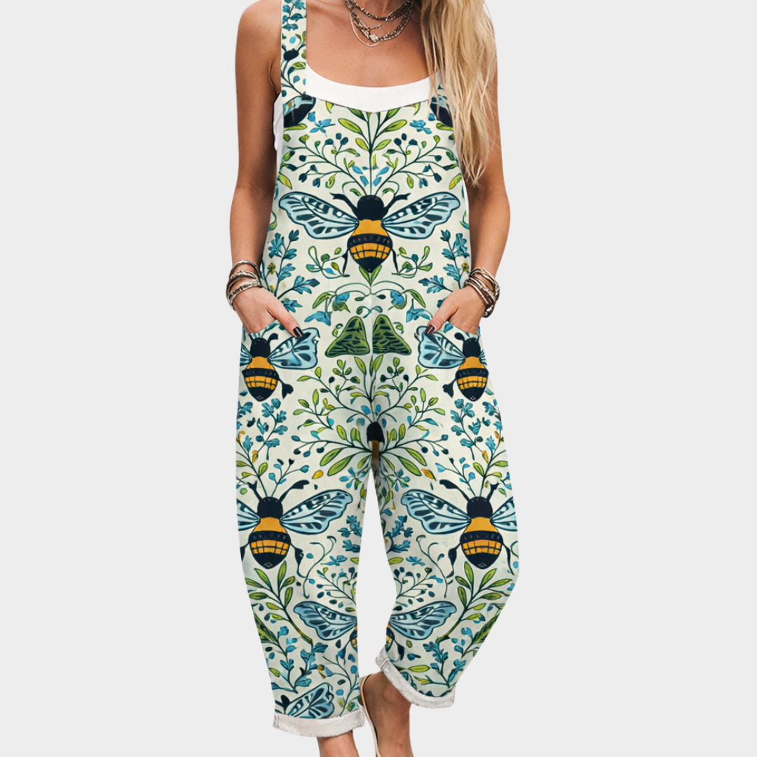A woman wearing relaxed bee-and-vine print overalls with adjustable straps on a warm day.
