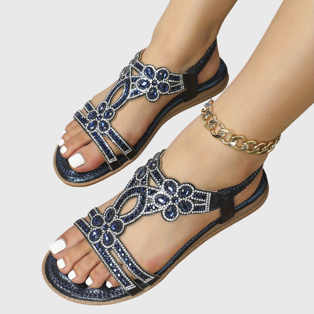 A woman wearing sky blue jewelled sandals with sparkling stones across the straps and a stretchy slingback.