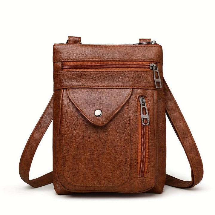 A woman wearing a compact vintage crossbody bag across her body while walking through town.