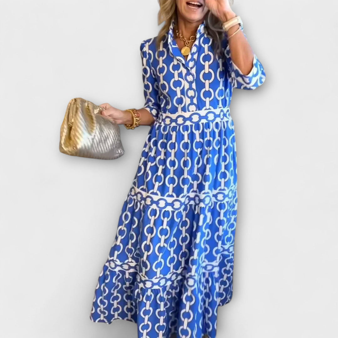 A woman wearing a flowing chain print midi dress that drapes elegantly as she walks.
