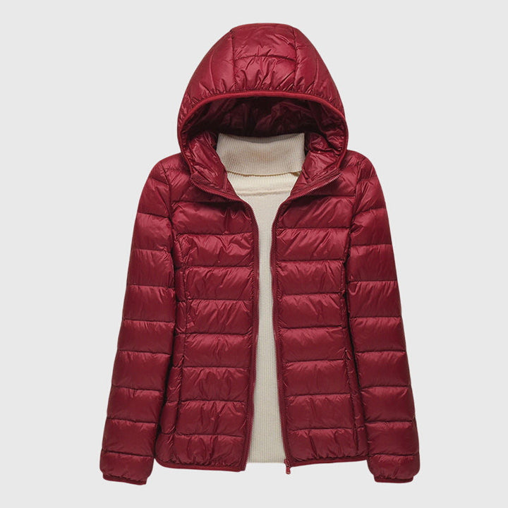 A woman wearing a lightweight padded jacket with a hood, outdoors on a cool day