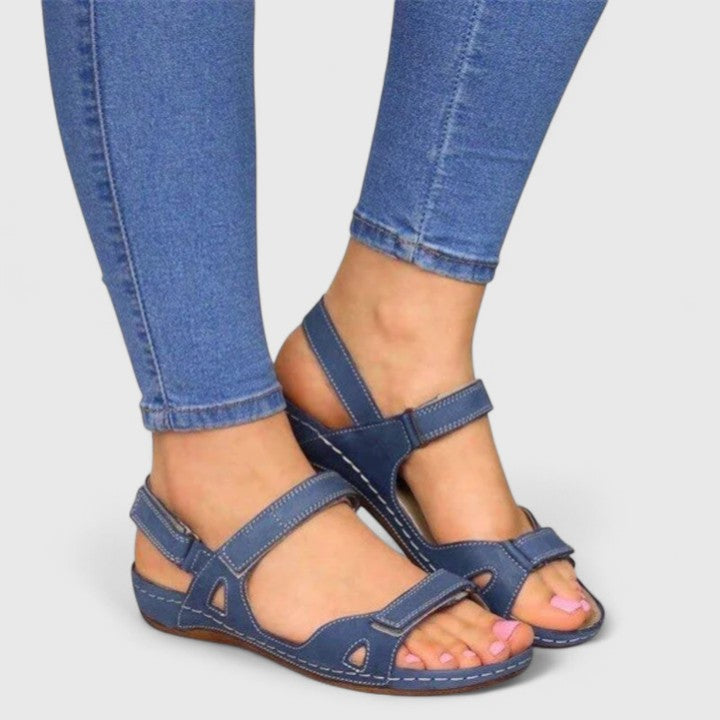 A woman walking through town in tan flat comfort sandals, relaxed and at ease.