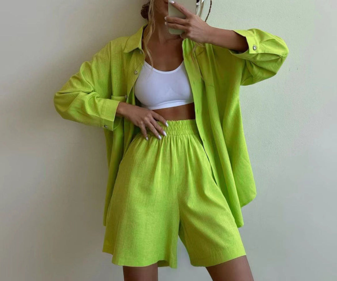 A woman wearing an oversized button-up shirt with matching high-waisted shorts.