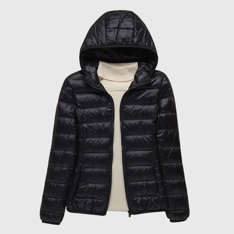 A woman wearing a lightweight padded jacket with a hood, outdoors on a cool day