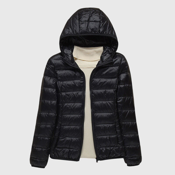A woman wearing a lightweight padded jacket with a hood, outdoors on a cool day