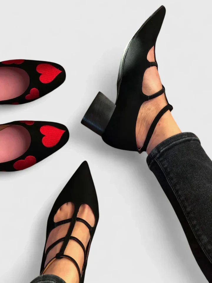 A woman walking through the city in black pointed-toe block heels with slim ankle straps, relaxed and confident.