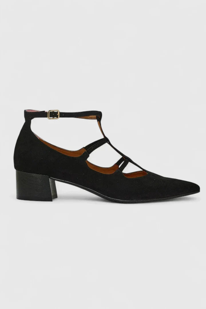 A woman walking through the city in black pointed-toe block heels with slim ankle straps, relaxed and confident.