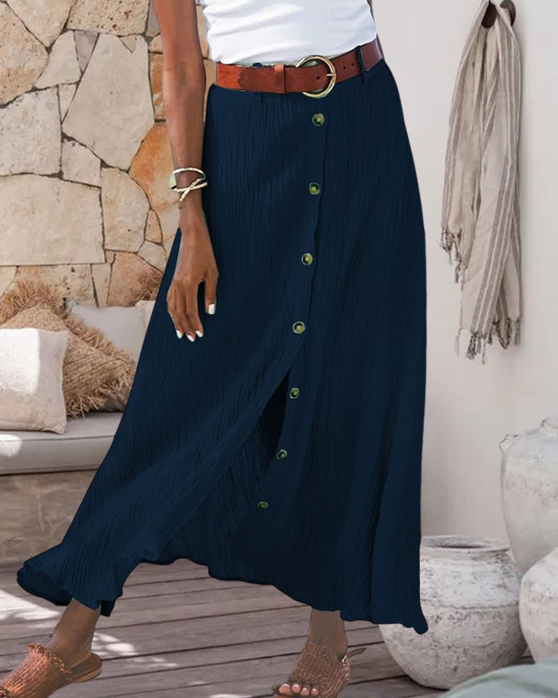Woman wearing a flowing high-waisted button skirt with a tucked-in top, walking outdoors.