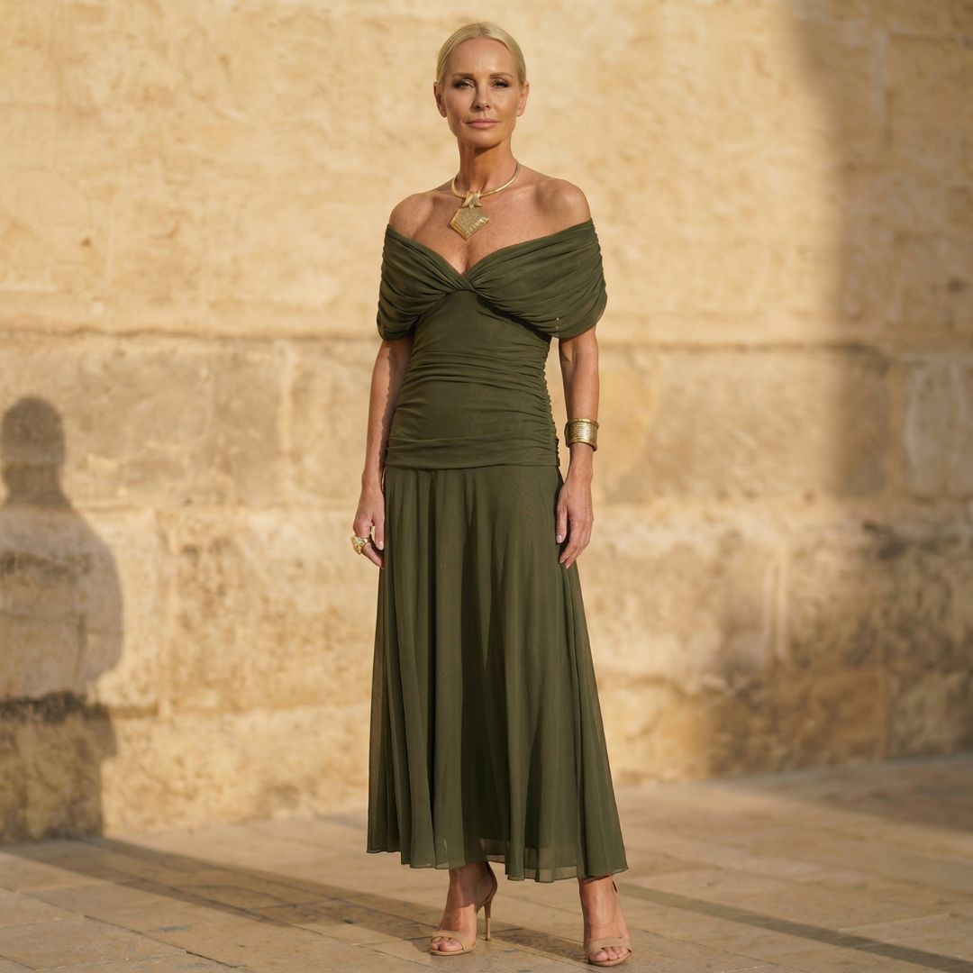 A woman wearing an elegant flowing olive green dress at an occasion.