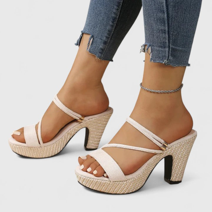 A woman wearing black adjustable strappy heels, standing gracefully in an elegant outfit.