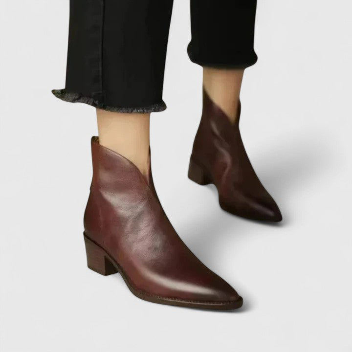 Woman wearing black elegant boots with tailored pants on a city footpath.