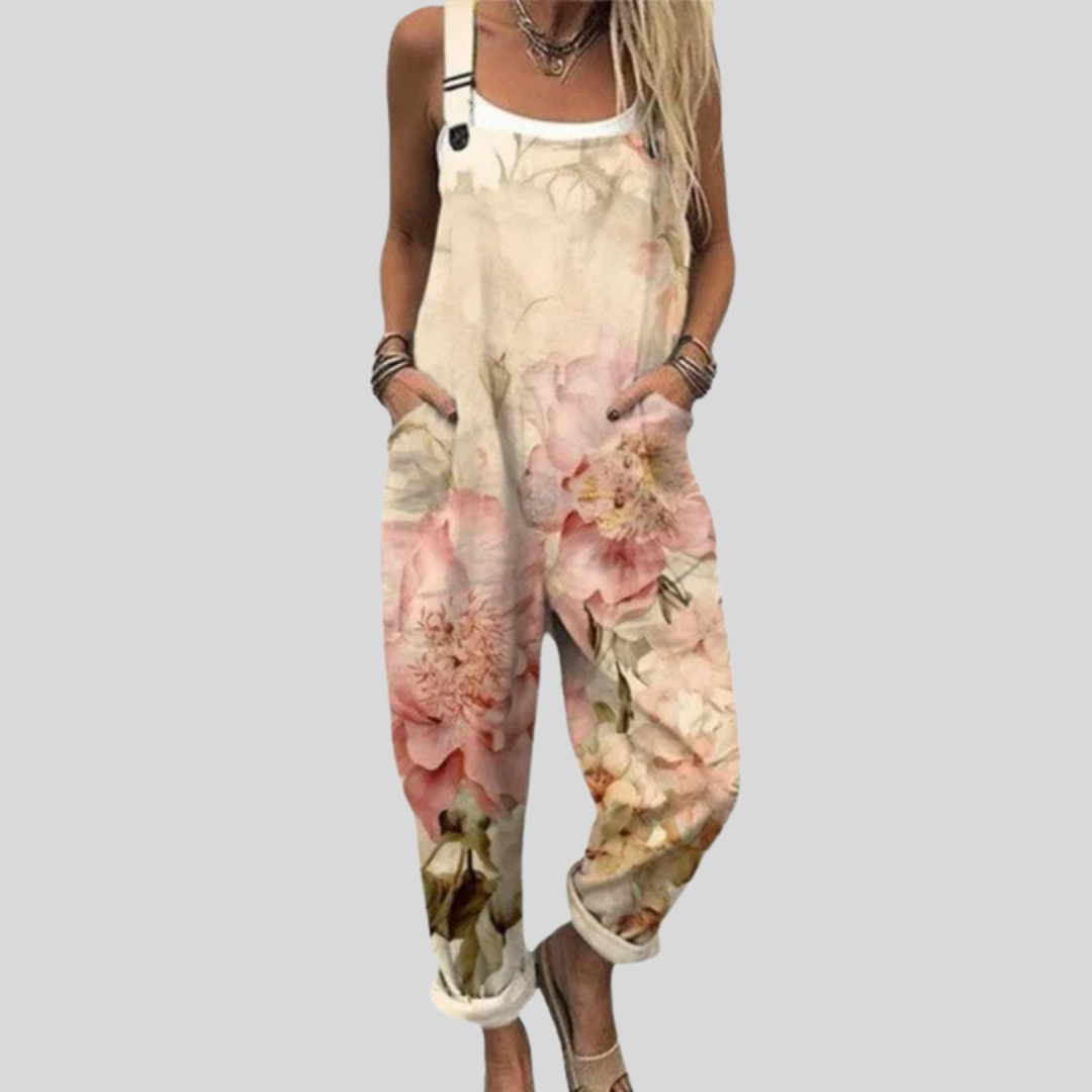 Woman wearing cream overalls printed with large watercolour roses in soft pink and peach, standing relaxed.