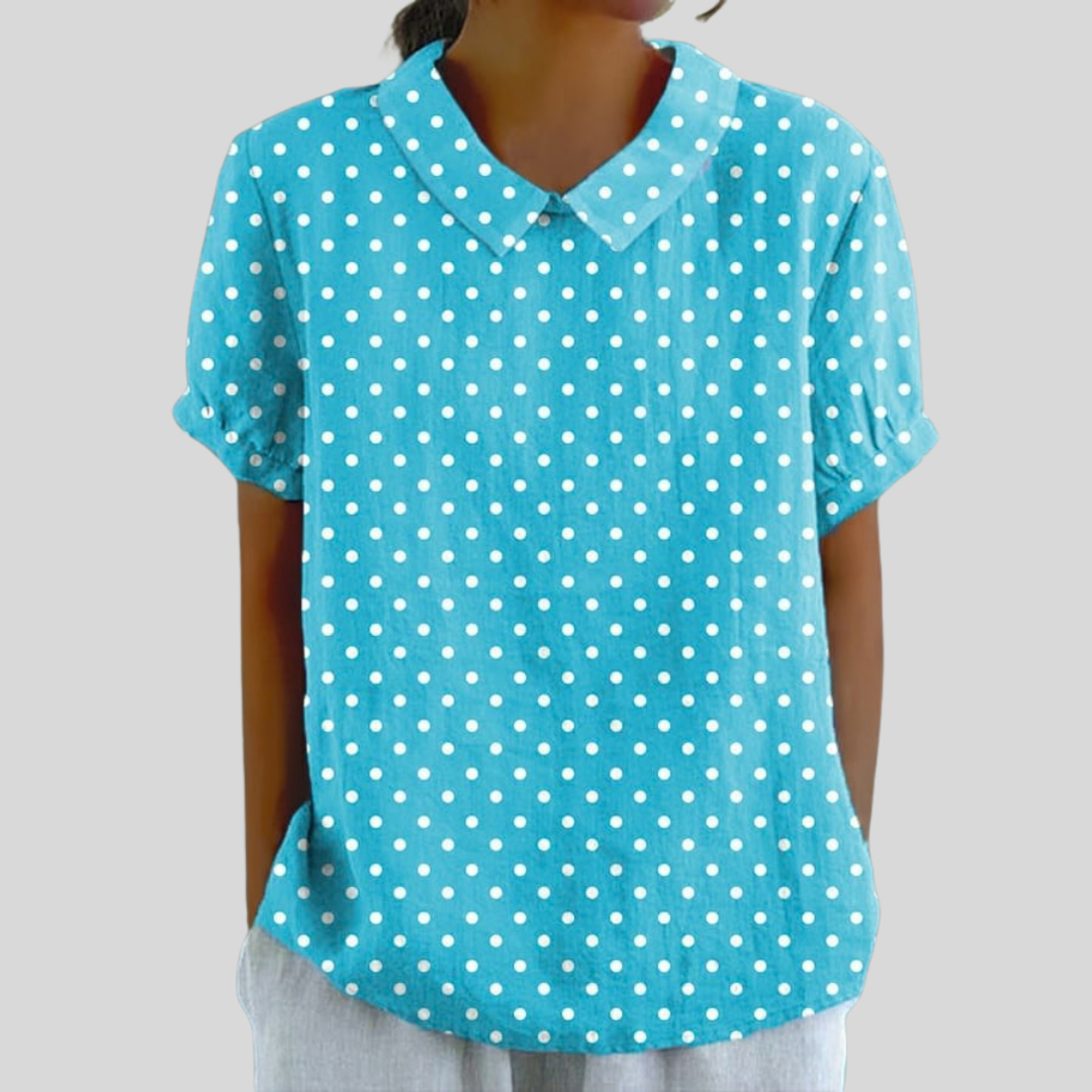 A woman wearing a soft turquoise polka dot top with a structured polo collar, looking feminine and elegant.