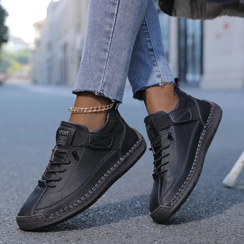 A woman wearing white lace-up orthopaedic sneakers with an adjustable strap.