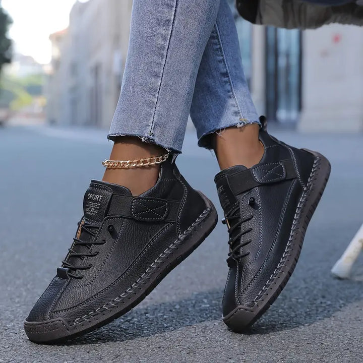 A woman wearing white lace-up orthopaedic sneakers with an adjustable strap.
