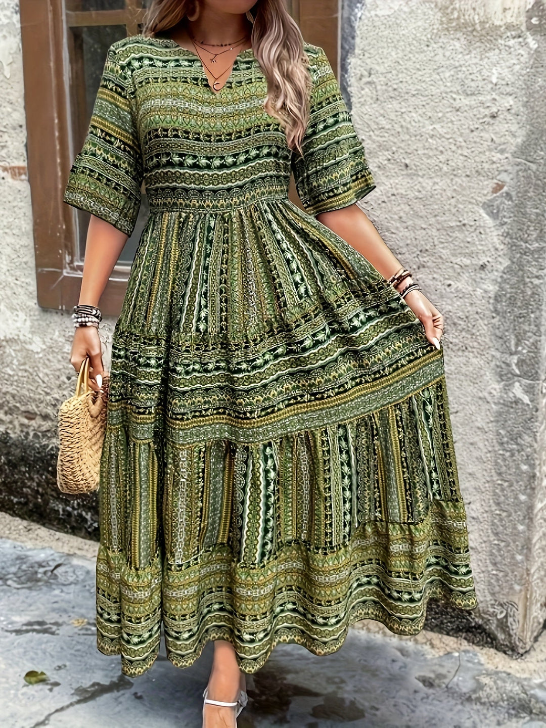 Woman wearing a flowing bohemian maxi dress with intricate pattern and ruffled details.