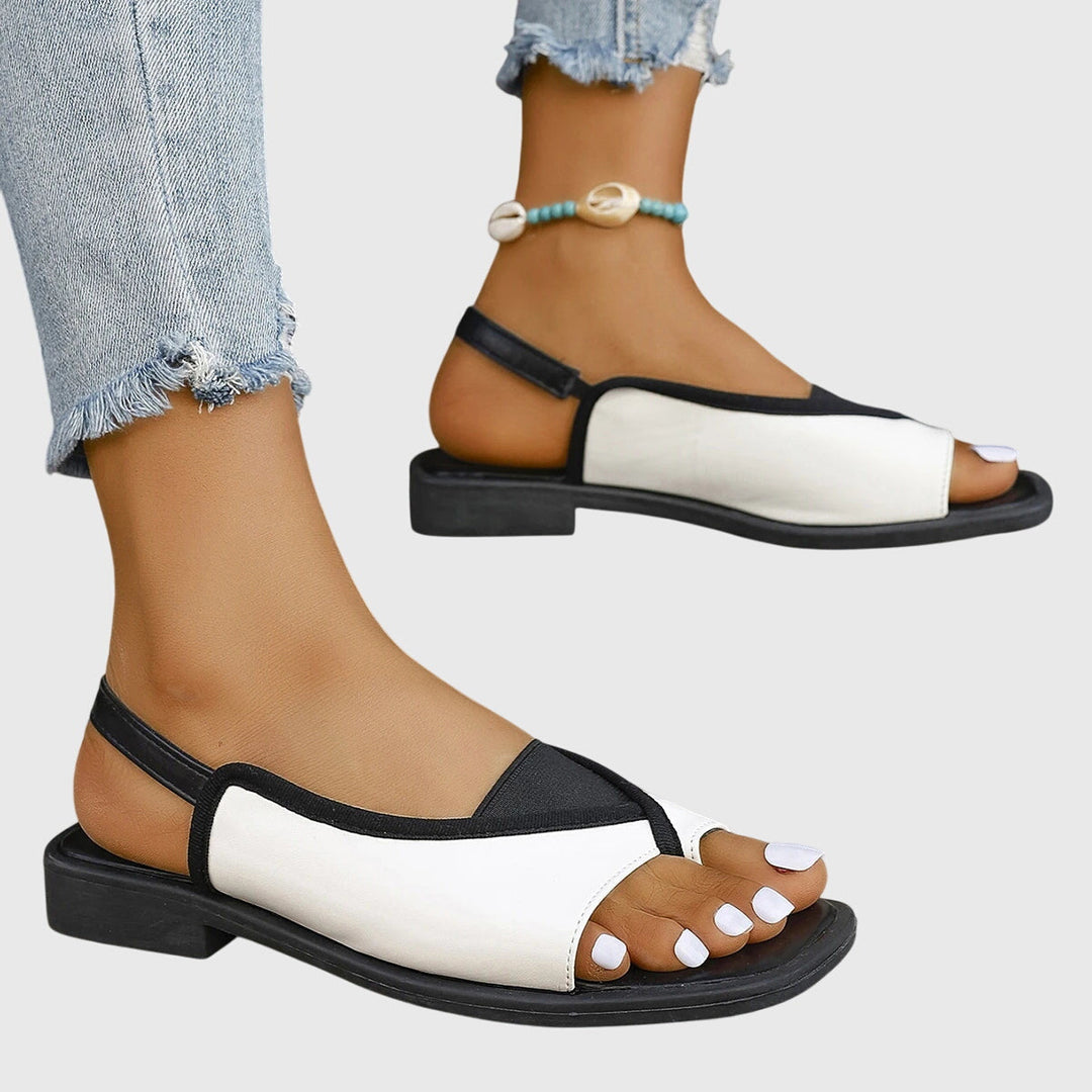 A woman wearing bold two-tone slide sandals on a warm city break.