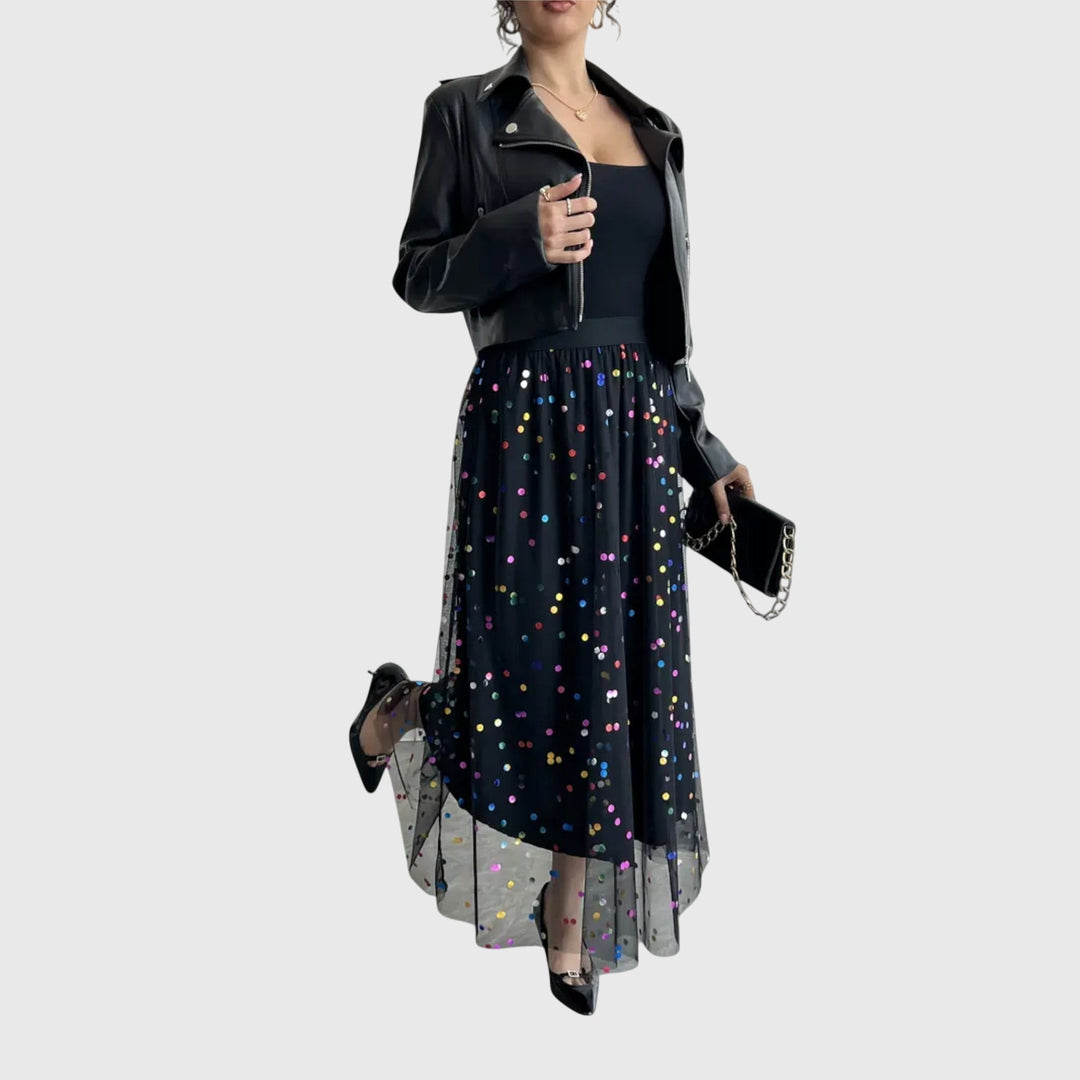 A woman in a black pleated skirt covered in multicoloured sparkling confetti dots, styled for an evening out.